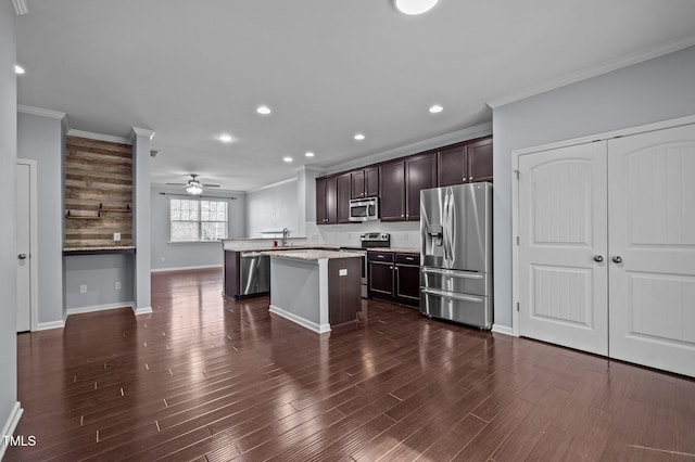 kitchen with dark brown cabinetry, ornamental molding, a center island, stainless steel appliances, and a sink