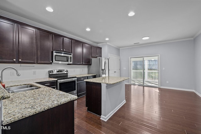 kitchen featuring stainless steel appliances, a sink, ornamental molding, a center island, and dark wood finished floors