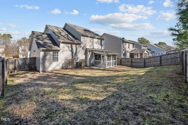 rear view of property featuring a sunroom, a fenced backyard, and a yard