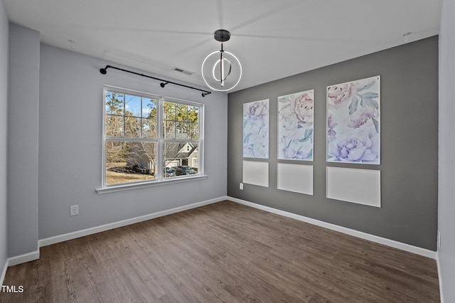 spare room featuring visible vents, baseboards, and wood finished floors