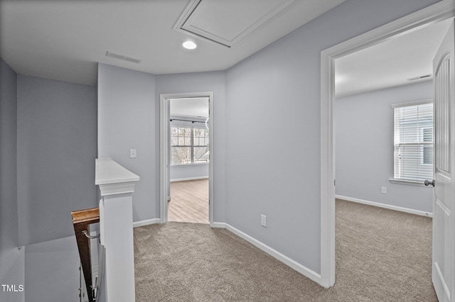 hallway featuring carpet, baseboards, visible vents, and an upstairs landing