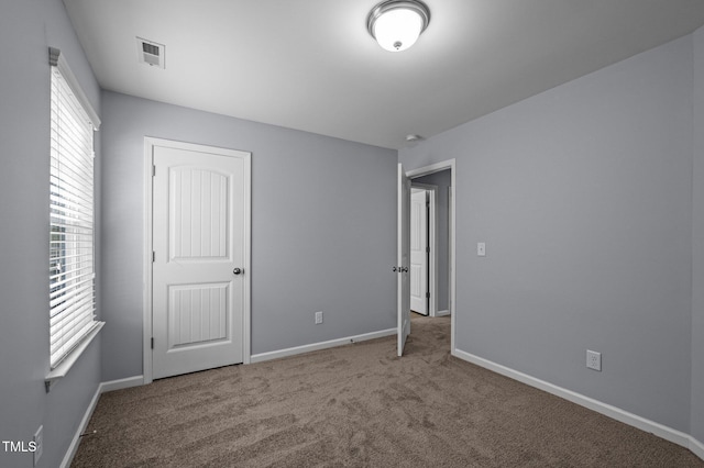 unfurnished bedroom with carpet flooring, visible vents, and baseboards