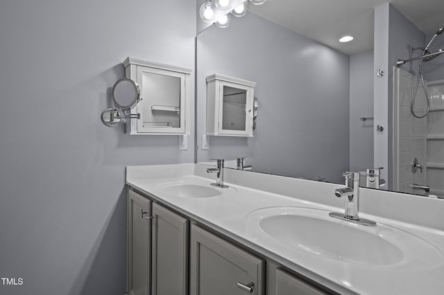 bathroom featuring double vanity, walk in shower, and a sink