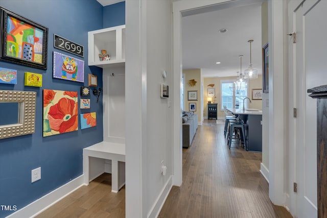 hallway featuring a sink, light wood-style flooring, and baseboards