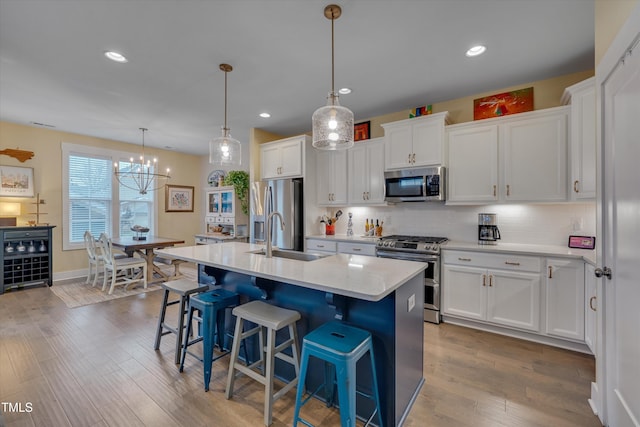 kitchen with an island with sink, white cabinetry, appliances with stainless steel finishes, and a sink