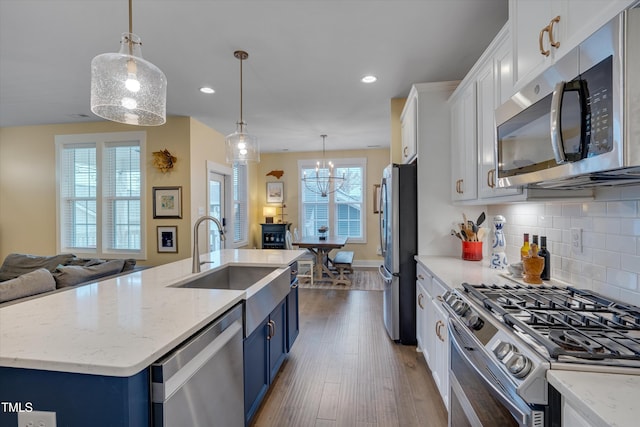 kitchen with open floor plan, stainless steel appliances, blue cabinetry, and hanging light fixtures