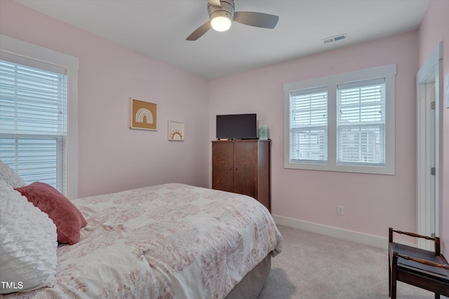 bedroom featuring baseboards, visible vents, a ceiling fan, and light colored carpet