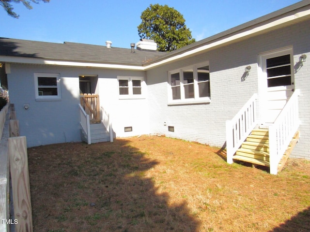 back of property with crawl space, a lawn, and brick siding