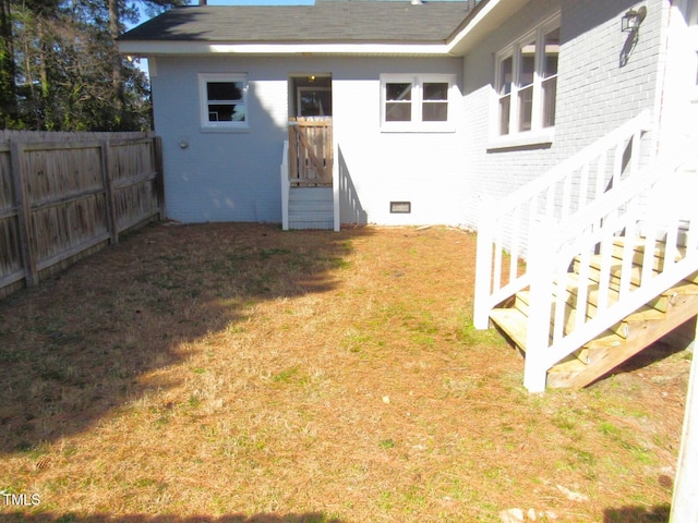 rear view of property with crawl space, a yard, fence, and brick siding