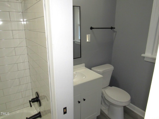 bathroom featuring toilet, washtub / shower combination, vanity, and baseboards