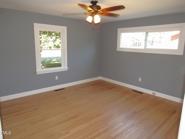 empty room featuring light wood-type flooring, baseboards, and visible vents