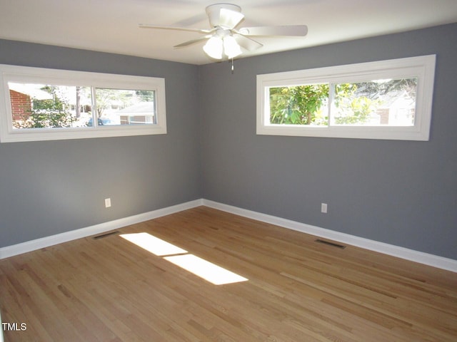 unfurnished room featuring visible vents, light wood-style flooring, a wealth of natural light, and baseboards