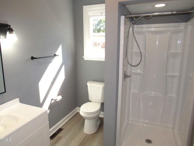 bathroom with toilet, wood finished floors, visible vents, vanity, and a stall shower