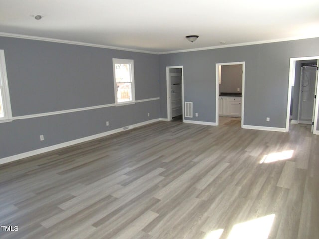 unfurnished bedroom with ornamental molding, visible vents, a spacious closet, and baseboards