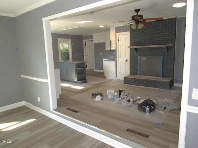 unfurnished living room featuring light wood finished floors, ornamental molding, a fireplace, and baseboards