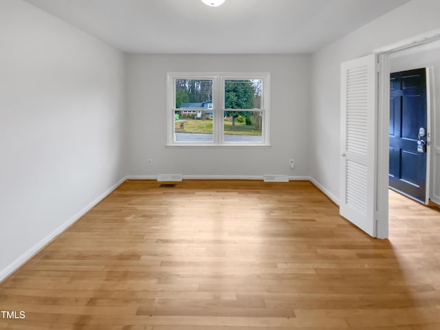 spare room featuring light wood-style floors, visible vents, and baseboards