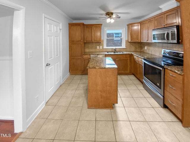kitchen with appliances with stainless steel finishes, a center island, brown cabinetry, and a sink