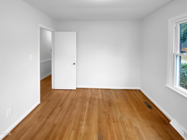 unfurnished room with light wood finished floors, visible vents, and baseboards