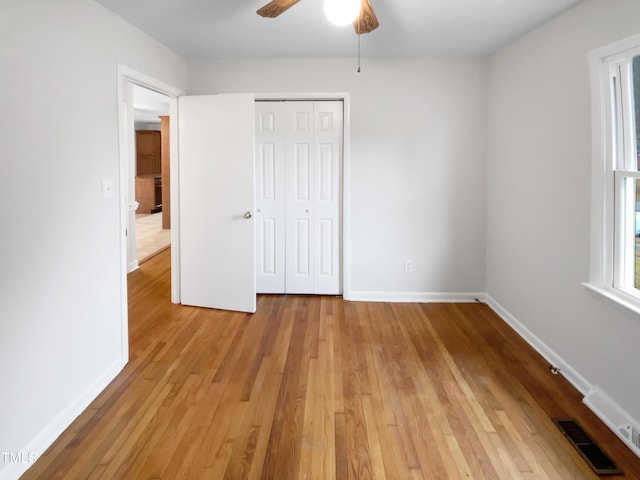 unfurnished bedroom featuring baseboards, visible vents, ceiling fan, light wood-type flooring, and a closet