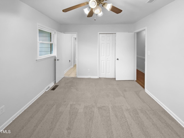 unfurnished bedroom with a closet, light colored carpet, visible vents, and baseboards