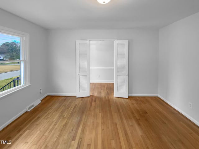 unfurnished room featuring light wood-style flooring, visible vents, and baseboards