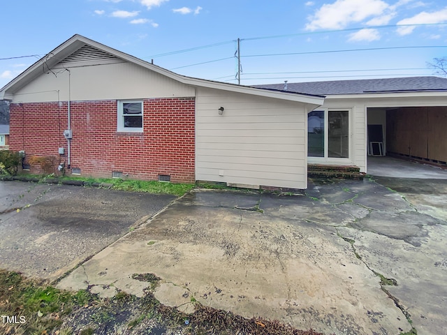 back of property featuring roof with shingles, brick siding, and crawl space