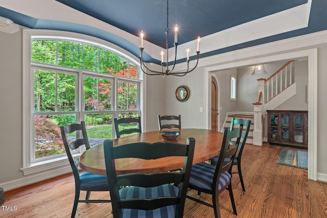 dining space with light wood finished floors, stairway, baseboards, a chandelier, and arched walkways