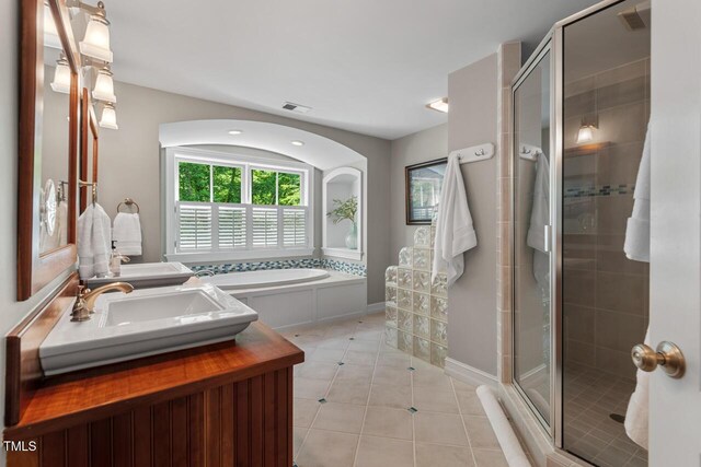 bathroom featuring a shower stall, a garden tub, tile patterned floors, and double vanity
