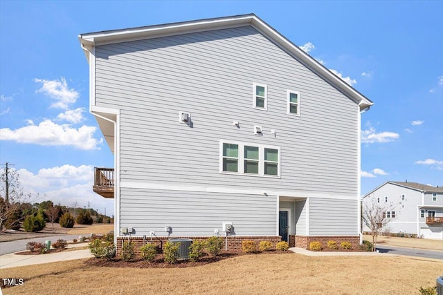 rear view of house with a yard, a balcony, and central air condition unit