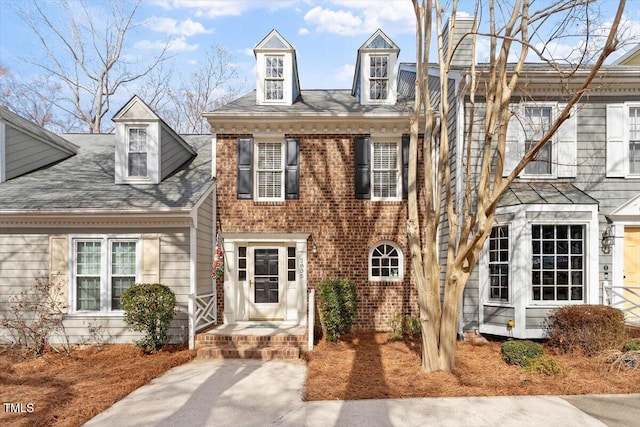 view of front of property featuring brick siding and a chimney