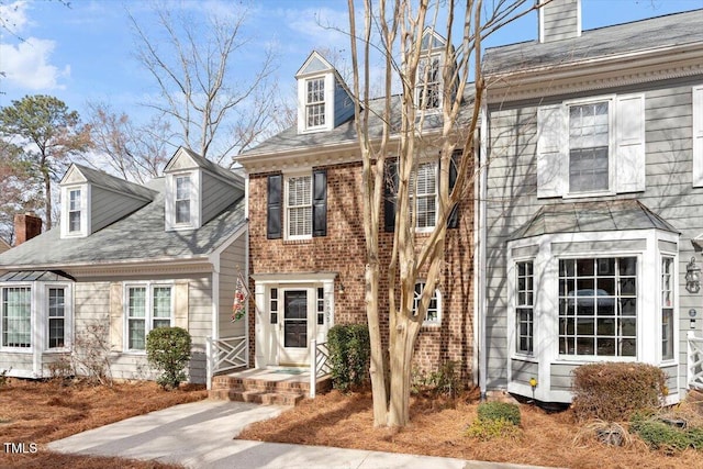 view of front of house featuring brick siding and a chimney