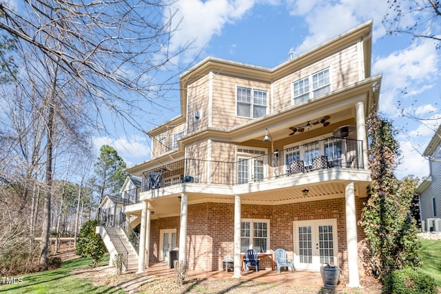 rear view of house featuring a balcony, brick siding, stairs, french doors, and a patio area