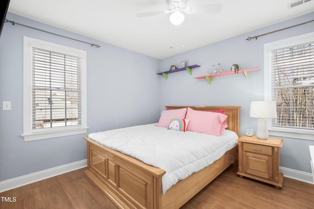 bedroom with ceiling fan, wood finished floors, visible vents, and baseboards