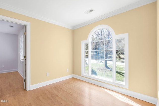 unfurnished room with light wood-style floors, a wealth of natural light, visible vents, and baseboards