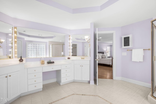 ensuite bathroom featuring vanity, baseboards, a shower stall, a tray ceiling, and ensuite bath