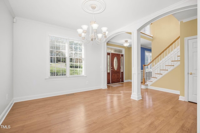 foyer featuring stairway, light wood-style flooring, arched walkways, and ornamental molding