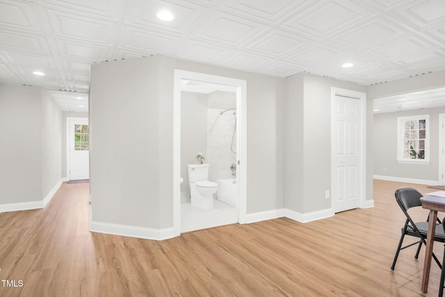 interior space featuring an ornate ceiling, light wood-style floors, and baseboards