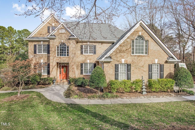 view of front facade with brick siding and a front yard