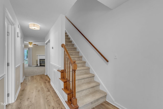 410 Oak Run Dr, Raleigh, NC 27606 - staircase featuring a glass covered fireplace, wood-type flooring, and ceiling fan