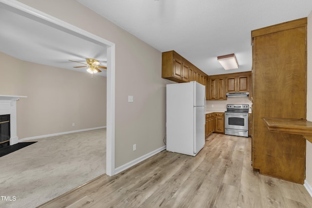410 Oak Run Dr, Raleigh, NC 27606 - kitchen with freestanding refrigerator, stainless steel range oven, brown cabinetry, under cabinet range hood, and a ceiling fan