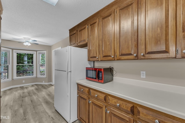 410 Oak Run Dr, Raleigh, NC 27606 - kitchen featuring brown cabinetry, a textured ceiling, a ceiling fan, light wood-style floors, and light countertops