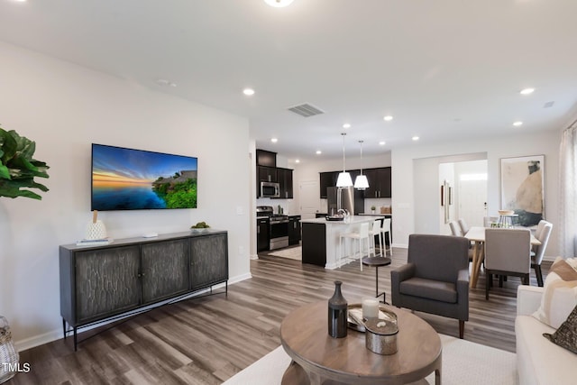 living area featuring baseboards, dark wood-style flooring, visible vents, and recessed lighting