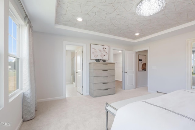 bedroom featuring baseboards, a tray ceiling, a walk in closet, and light colored carpet