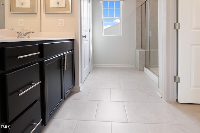 bathroom with tile patterned flooring, baseboards, vanity, and a shower stall