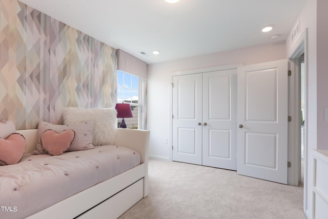 bedroom with a closet, light colored carpet, and visible vents