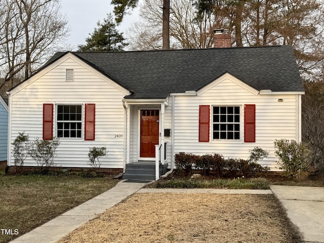 view of front facade with roof with shingles and a chimney