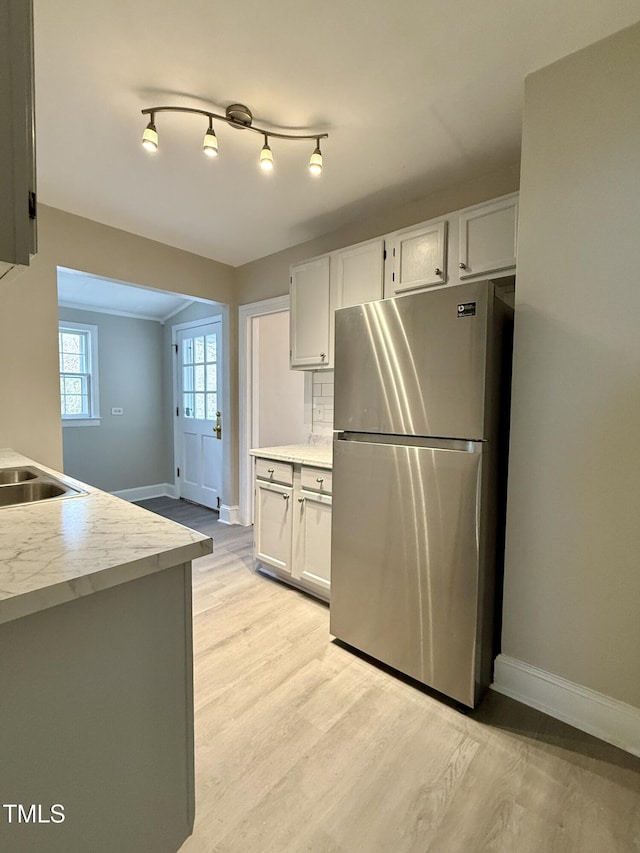 kitchen featuring light countertops, white cabinets, light wood-type flooring, and freestanding refrigerator