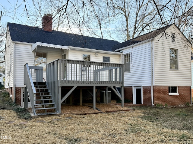 back of property featuring stairway, roof with shingles, a deck, and a chimney