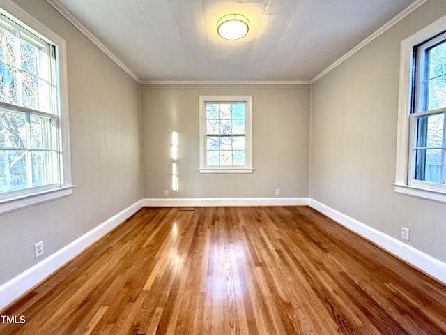 empty room featuring baseboards, wood finished floors, and ornamental molding