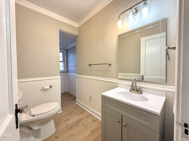 bathroom featuring toilet, wood finished floors, wainscoting, crown molding, and vanity